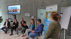 Fünf Personen sitzen auf Stühlen. Sie sind von vorne zu sehen. Es sind Praktiker aus Landwirtschaft und Bäckerhandwerk. Sie sitzen in einem Raum und sprechen über den Austausch von Wissenschaft und Praxis.